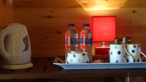 two coke bottles sitting on a table next to cups at Woodbatch Camping & Glamping in Bishops Castle