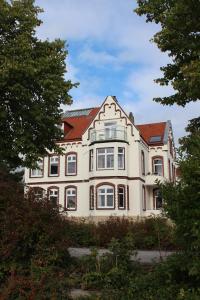 ein großes weißes Haus mit rotem Dach in der Unterkunft Ferienwohnungen Schlei 42 in Schleswig