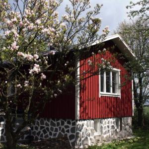 czerwony dom z białym oknem i drzewem w obiekcie Lilla Huset på Slätten B&B w mieście Lund