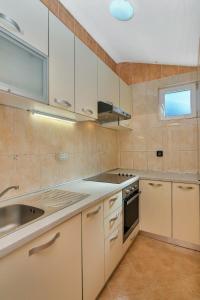 Apartments Rubin في Zastražišće: مطبخ مع دواليب بيضاء ومغسلة