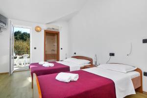 a room with two beds with red and white sheets at Apartments Rubin in Zastražišće