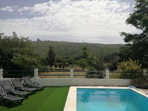 a swimming pool with chairs and a fence and a field at Montejunto Villas - Casa do Plátano in Cadaval