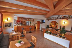 a living room with tables and chairs and a kitchen at Hotel Vigo in Vigo di Fassa