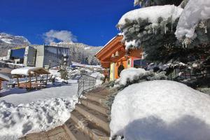 dom pokryty śniegiem przed górą w obiekcie Hotel Vigo w mieście Vigo di Fassa