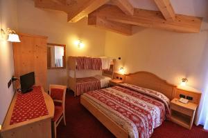 1 dormitorio con 1 cama y escritorio con TV en Hotel Vigo en Vigo di Fassa
