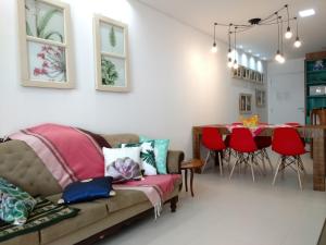 a living room with a couch and a table with red chairs at Apartamento Espelho das Águas in Florianópolis