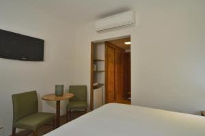 ein Schlafzimmer mit einem Bett, 2 Stühlen und einem TV in der Unterkunft Hotel Magique Le Canton in Teresópolis