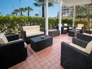 a patio with wicker chairs and tables and palm trees at Hotel Marisa in Riccione