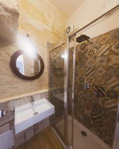 bagno con doccia, lavandino e specchio di Cave Garden rooms a Favignana