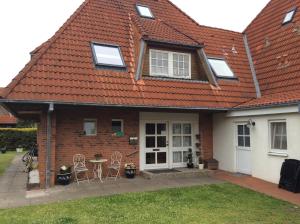 ein Haus mit einem roten Dach, einem Tisch und Stühlen in der Unterkunft Ferienhaus Knippschild in Norderney