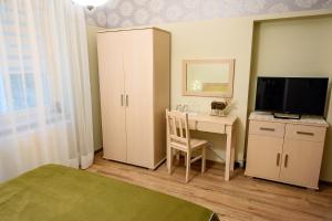 a bedroom with a desk and a tv and a bed at Willa Poranek in Krynica Zdrój