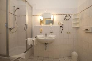 ein weißes Bad mit einem Waschbecken und einer Dusche in der Unterkunft AKZENT Waldhotel Spa Rügen in Göhren