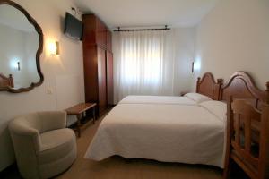 a bedroom with a bed and a chair and a mirror at Hotel Cabeza in Noreña