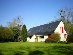 una casa blanca con techo negro en un césped verde en La Petite Londe, en Biéville-Beuville