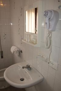 bagno con lavandino e asciugacapelli appeso al muro di Hotel Caravel a Sottomarina