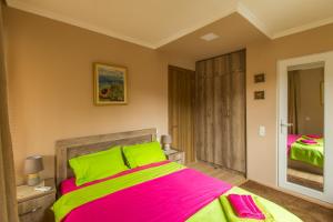 a bedroom with a large bed with green and pink sheets at Mereti in Borjomi