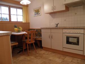 Il comprend une cuisine équipée d'une cuisinière et d'une table avec une chaise. dans l'établissement Flatscherhof, à San Lorenzo di Sebato