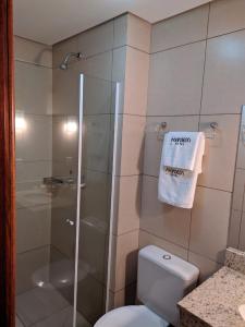 ein Bad mit einer Dusche, einem WC und einem Handtuch in der Unterkunft Hotel Aguadero in Passo Fundo