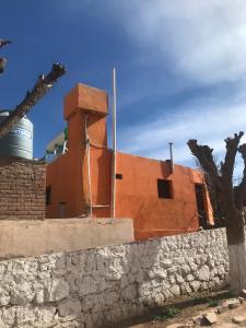 a building behind a stone wall with a tree at El Valle in Tilcara