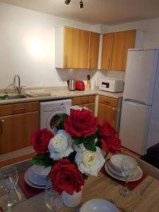 uma cozinha com uma mesa com rosas vermelhas e brancas em Vetrelax Basildon Crosse Apartment em Basildon