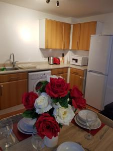 a kitchen with a table with red and white roses at Vetrelax Basildon Crosse Apartment in Basildon