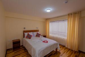 sypialnia z łóżkiem z białą pościelą i oknem w obiekcie Hawka Inka Hostal - Cusco w Cuzco
