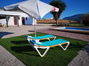 a beach chair and an umbrella on the grass at Alojamiento Rural - Finca Santa Margarita in Algar