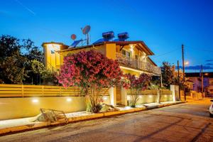 ein gelbes Haus mit Blumen davor in der Unterkunft Lazy Lizard in Néa Karváli