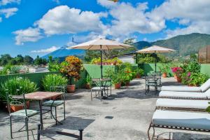 a row of tables and chairs with umbrellas on a patio at Posada San Vicente by AHS in Antigua Guatemala