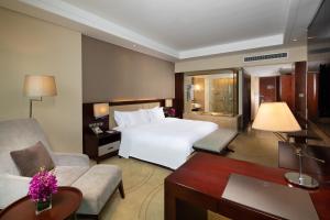 台州市にあるCrowne Plaza Taizhou, an IHG Hotelの白いベッドとデスクが備わるホテルルームです。