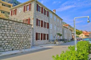 a stone building with red shuttered windows on a street at Luxury Waterfront Villa with Private Pool and Private Beach for 12 People in Kotor