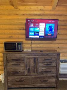 a television on top of a wooden cabinet with a microwave at Countryside Cabins in Panguitch