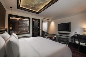 a bedroom with a white bed and a television at La Sinfonía del Rey Hotel & Spa in Hanoi