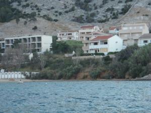 un grupo de casas en una colina junto a un cuerpo de agua en Apartments Ariana, en Pag