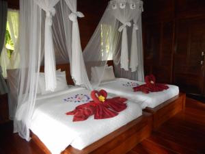- 2 lits dans une chambre avec des rideaux blancs et des peignoirs rouges dans l'établissement Kubu Alas Tunggal Villa, à Sidemen