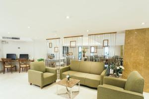 a living room with couches and chairs and a table at Thomson Hotel Huamark in Bangkok