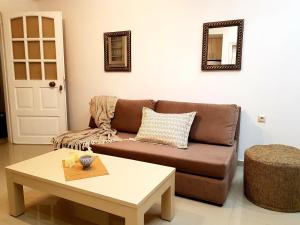a living room with a brown couch and a coffee table at Emmanouil airport beach apartment in Karteros