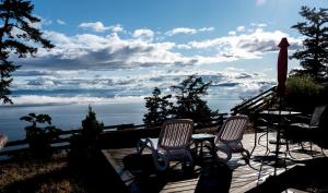 a deck with two chairs and a table and a umbrella at Shangri-La Oceanfront vacation home in Bedwell Harbour