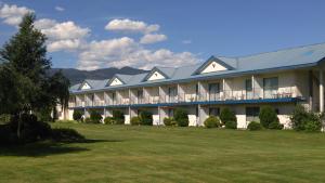 a large white building with a blue roof at Monashee Motel in Sicamous