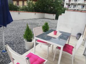 a glass table and chairs on a patio at Crystal Blue Apartments in Nea Kalikratia