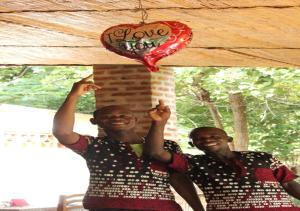 two men standing under a table with a heart balloon at Barefoot Lodge and Safaris - Malawi in Lilongwe