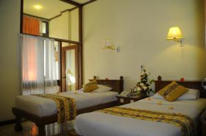 a hotel room with two beds and a christmas tree at Melasti Beach Resort & Spa Legian in Legian