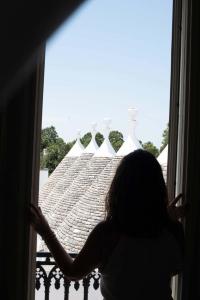 een vrouw die uit een raam naar een dak kijkt bij Relais Masseria Villa Cenci in Cisternino