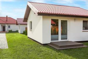 a white house with a porch and a yard at Cicha Dolina in Ustka