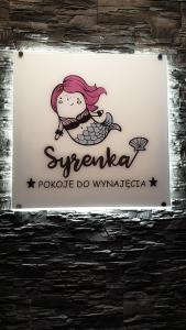 Una señal para una tienda con una sirena. en Pokoje Morska Syrenka, en Stegna