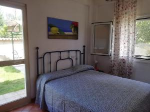 a bedroom with a bed with a blue comforter and two windows at Villa Ettore in Gardeládes