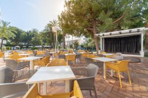 a restaurant with tables and chairs and a stage at Tropicana Hotel in Cala Millor +29 photos