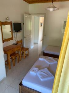 a room with two beds and a desk and a mirror at Filoxenia Kontogiannis in Lazaráta