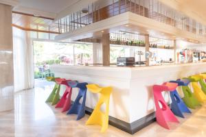 een bar met kleurrijke stoelen in een restaurant bij Hotel Millor Sol in Cala Millor