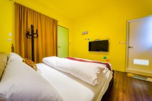 two beds in a room with a yellow wall at 梅花湖-陽光屋民宿 in Dongshan